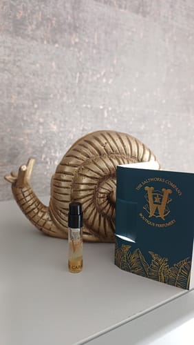 A customer's small Copacabana perfume tester vial sits on a white table next to its dark green packaging.