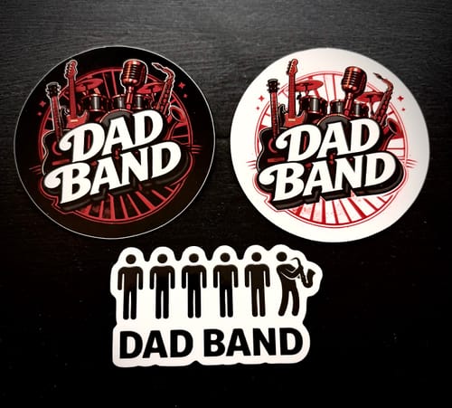 Customer's three custom vinyl stickers for a 'Dad Band', showing two circular designs and one die-cut design on a dark surface.