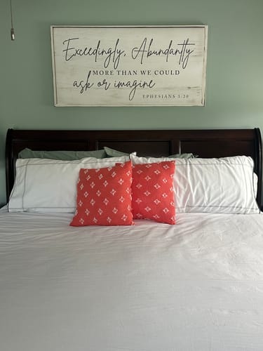 Customer's 'Exceedingly, Abundantly More' faith sign hanging on a green wall above the headboard of a bed.