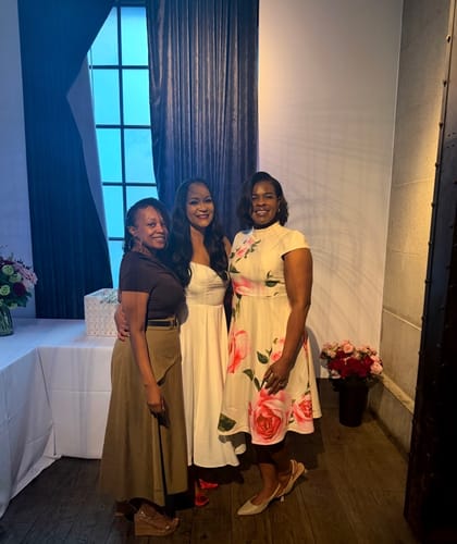Reviewer wearing the beautiful flower print midi dress, standing with two other people at an event.