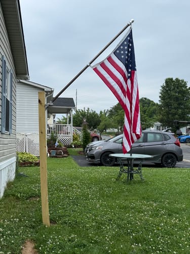 Customer's Prestige House Flag Pole displaying an American flag, mounted on a wooden post in a yard.