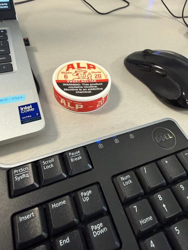 Reviewer's can of Sweet Nectar Nicotine Pouches on a desk next to a laptop and keyboard.