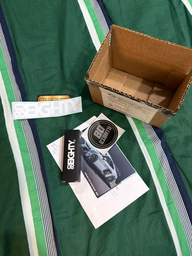 Customer's 80Eighty® Flashlight packaging, shipping box, and promotional stickers laid out after unboxing.