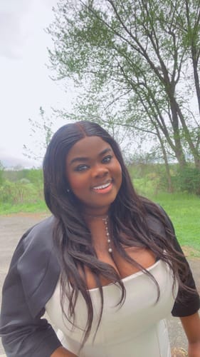 Close-up of a reviewer smiling while wearing the white Suiting Lace-Up Midi Dress and a black shrug outdoors.