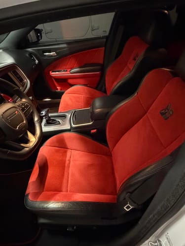 A customer's view of their clean Dodge Charger interior with red and black seats.
