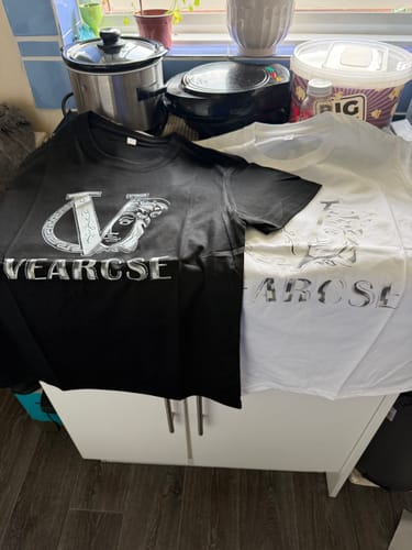 Customer's two luxury-inspired graphic t-shirts, one black and one white, laid out on a cabinet.