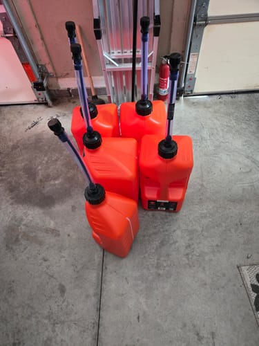 Customer shows four red gas cans with spouts sitting on a garage floor.