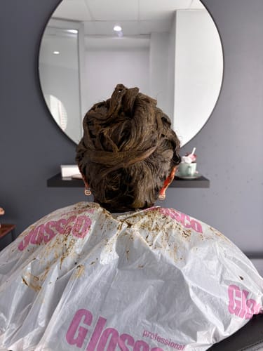 Clienta con el Tratamiento Capilar Polvo de Aloe Vera aplicado en su cabello recogido en un moño, visto desde atrás.