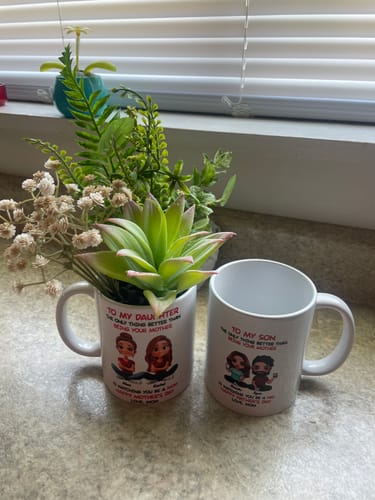Customer's personalized son mug next to a similar daughter mug used as a planter with artificial succulents on a counter.