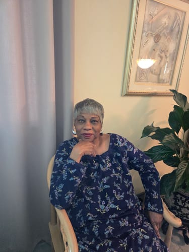 Reviewer seated indoors, wearing the short, salt & pepper Foxy Silver Wig MARY.