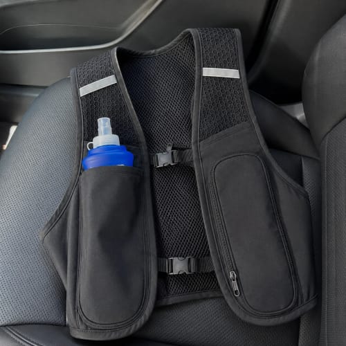 Recensione del RunVest nero, poggiato su un sedile d'auto con una borraccia blu in tasca.