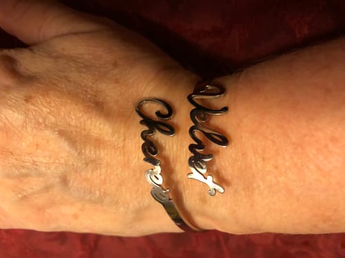A reviewer's wrist wearing the silver Personalized Two-Name Bangle with the names 'Chérie' and 'Velvet'.