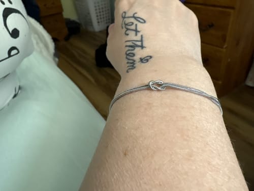 Close-up of a reviewer's wrist, wearing the simple Forever Knot Bracelet.
