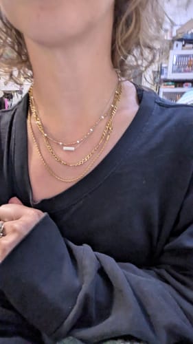 Customer wearing the gold Coco Rope Necklace layered with several other necklaces.
