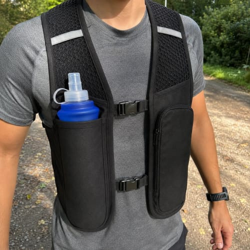 Recensore indossa il gilet da corsa RunVest nero, con una borraccia blu nella tasca frontale.