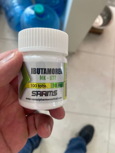 Cliente sosteniendo en la mano un frasco blanco de Ibutamoren MK-677, mostrando la etiqueta del producto.