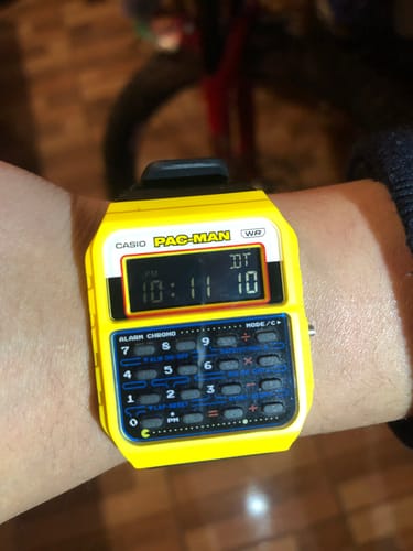 Cliente mostrando su reloj calculadora Casio Vintage PAC-MAN de color amarillo en la muñeca.