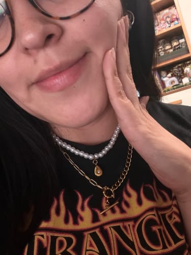 Clienta usando su Accesorio Sorpresa: un collar de perlas y una cadena dorada, puestos en capas.