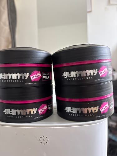 Customer shows four stacked tubs of Gummy Styling Wax in black packaging with pink labels.