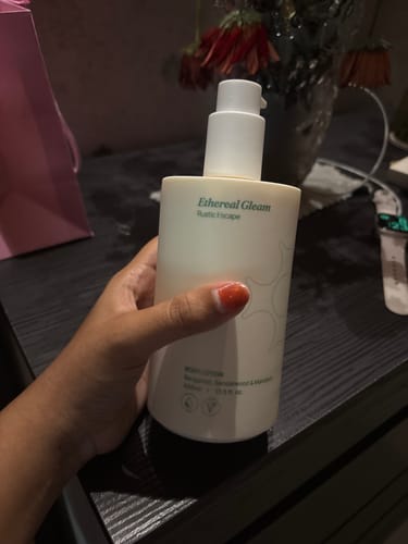 Reviewer's hand holding the Ethereal Gleam Body Lotion in Rustic Escape.