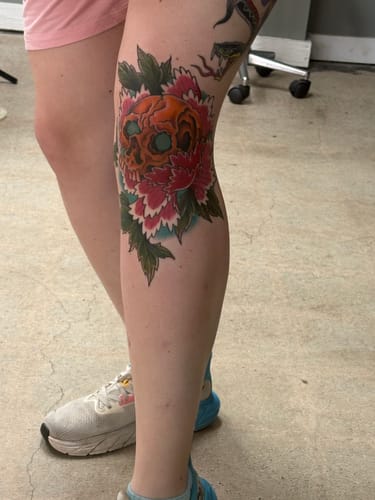 Customer displays a new, colorful skull tattoo on their knee, done with the help of Miracle Numb Spray.