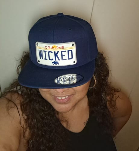 Reviewer wearing a navy blue California Sunny Plate Hat with the custom text "WICKED" on the license plate patch.