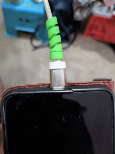 Close-up of a customer's green cable protector wrapped around a charger plugged into a phone.