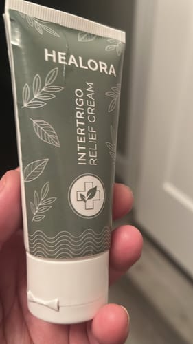 Customer holding a green and white tube of Healora Intertrigo Relief Cream.