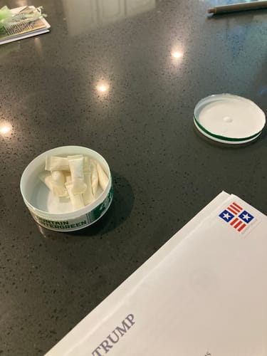 Customer's open tin of Mountain Wintergreen Nicotine Pouches on a dark countertop, with several pouches visible inside.
