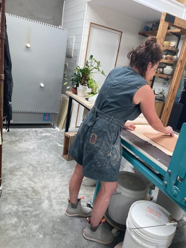 Customer from behind wearing the green Cropped Yard Suit while working in a studio.