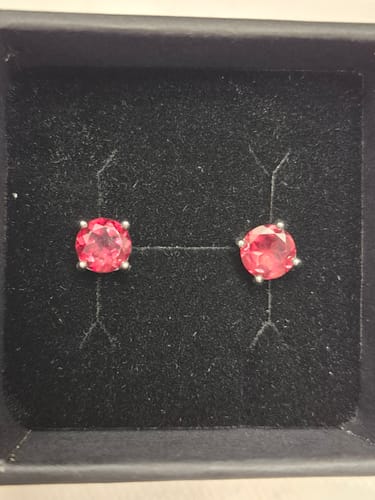 Avis d'un client montrant une paire de clous d'oreilles avec une pierre rose dans un écrin noir.