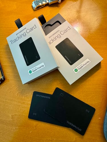 Customer's two black SPOTMINDERS Tracking Cards and their packaging displayed on a wooden table.
