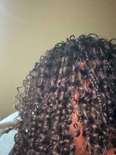 Close-up of a reviewer's Burmese Spanish Curl hair styled in dark, curly micro knots.