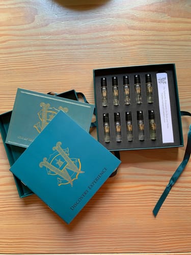 Reviewer's Discovery Set opened, showing elegant perfume samples inside the teal presentation box on a wooden table.