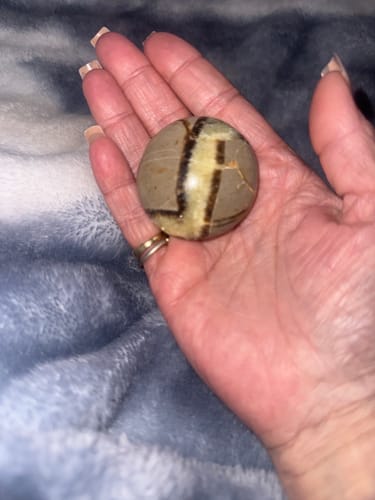 Customer holding a round, patterned Monthly Crystal in their open palm.
