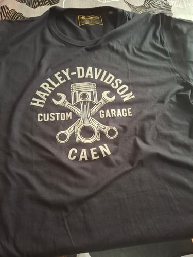 Photo d'un client montrant le T-Shirt Custom Garage noir posé à plat, avec son logo imprimé sur la poitrine.