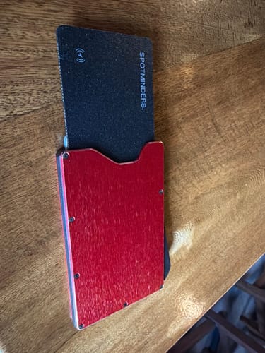 Customer's black SPOTMINDERS Tracking Card shown inside a red metal card holder on a wooden table.