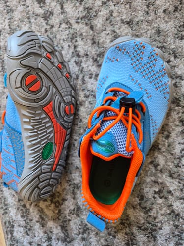 Kundenfoto: Ein Paar hellblaue Kinder Free I Barfußschuhe mit orangen Details, die die Sohle und die Innenseite zeigen.