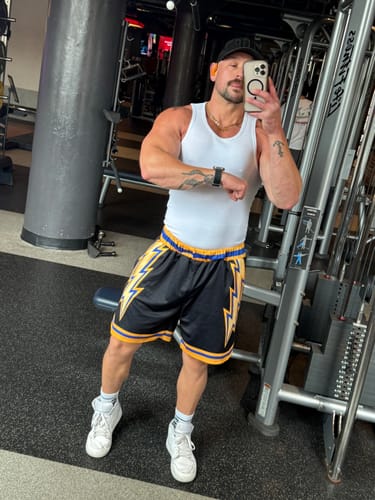 Reviewer at the gym showing the snug fit of the white Premium Ultra-Soft Cotton Fitted Tank.
