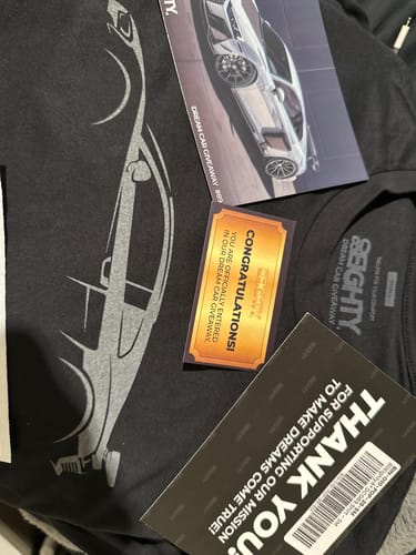 Customer's black 80Eighty DCG89 Shirt with a car graphic laid out with contest entry cards.