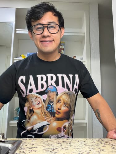Cliente sonriendo mientras luce la camiseta negra de S. Carpenter.