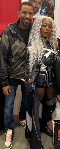 Reviewer wearing the long, curly Sensationnel Lemelas Wig as part of a cosplay outfit.