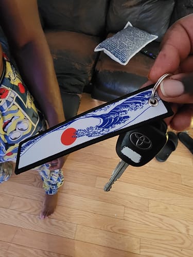 Customer holds the embroidered TOKYO WAVE JET TAG attached to a Toyota car key.