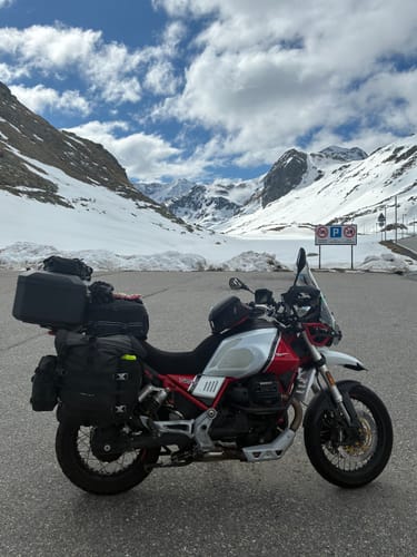 Reviewer's MotoGuzzi motorcycle with a Wind Rider Seat Cover, parked on a road in a snowy mountain pass.