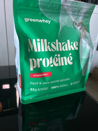 Avis d'un client montrant le sachet de Milkshake protéiné saveur fraise sur une surface noire.