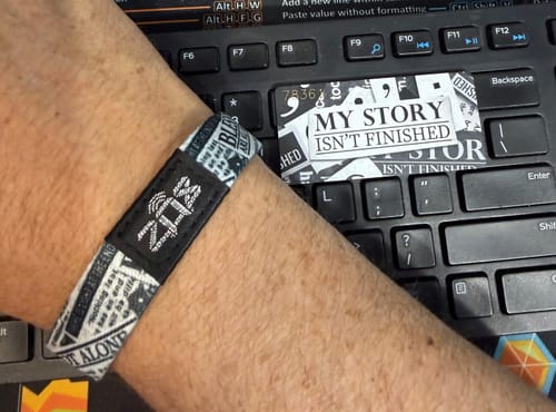 Reviewer showing their "My Story Isn't Finished Bracelet" on their wrist, with the matching card on a keyboard.