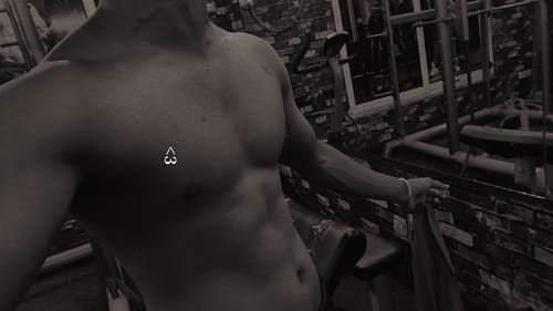 Reviewer in a gym showing their muscular torso after using Wellcore Creatine.