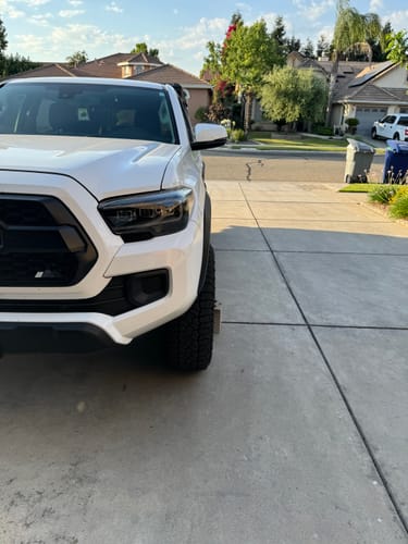 A reviewer's white Tacoma truck showing a wider wheel stance after installing the 1.25" hubcentric wheel spacers.