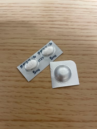 購入者によるAGA・ED対策セットのレビュー写真。木製のテーブルの上に置かれたタダラフィル5mg錠のブリスターパック。