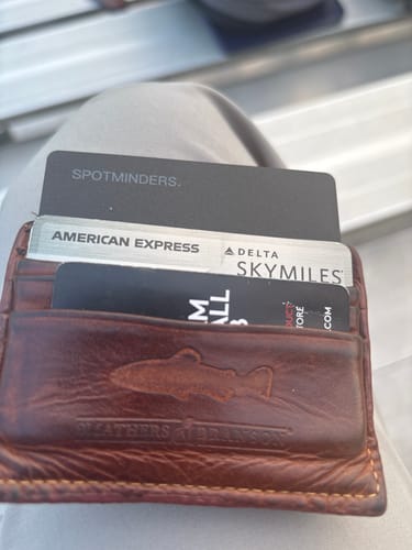 Customer's black SPOTMINDERS tracking card shown inside a brown leather wallet with other cards.
